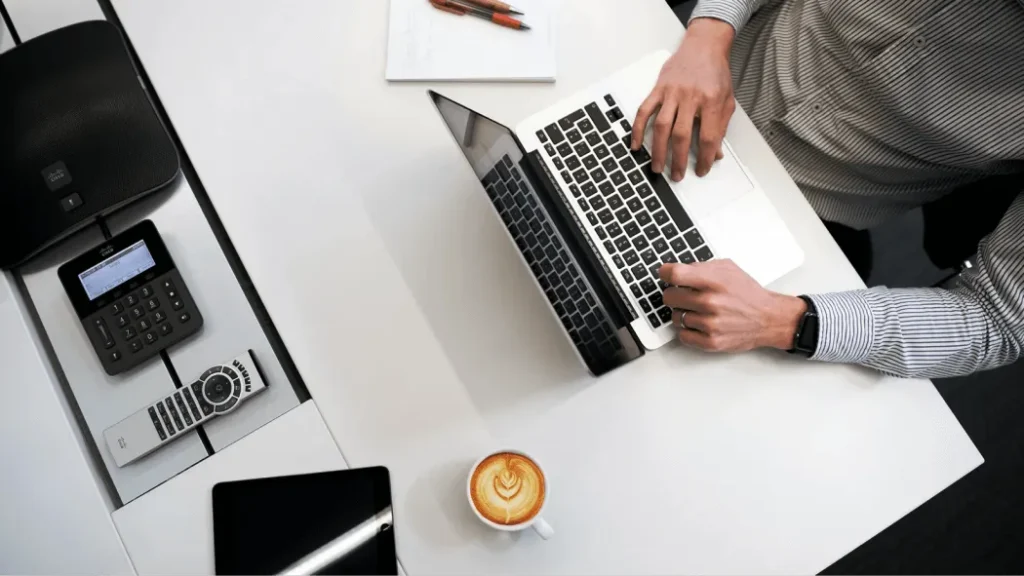 Professional working on laptop with coffee and office tools, representing Essential Digital Agency’s approach to local SEO for New Brunswick businesses.